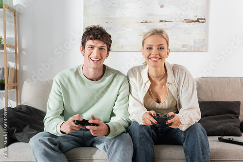 KYIV, UKRAINE - OCTOBER 24, 2022: young couple holding joysticks while playing video game 