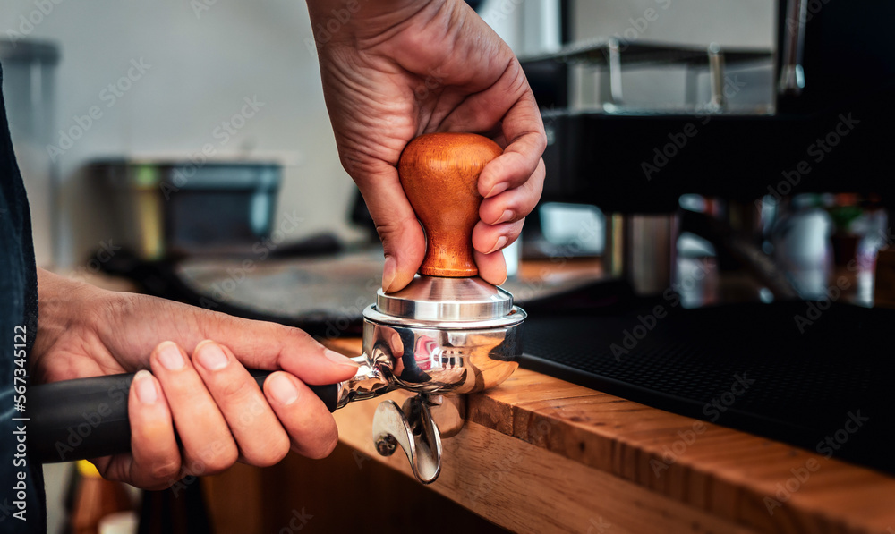 Close-up of hand Barista cafe making coffee with manual presses ground coffee using tamper at the coffee shop Close-up of hand Barista cafe making coffee with manual presses ground coffee using tamper at the coffee shop