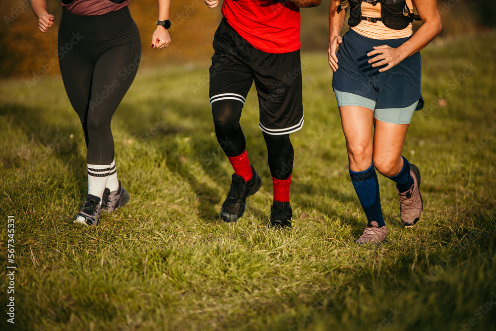 Young athletic people participate in marathon race on the mountain. Focus on the legs and bottom part of the body Young athletic people participate in marathon race on the mountain. Focus on the legs and bottom part of the body