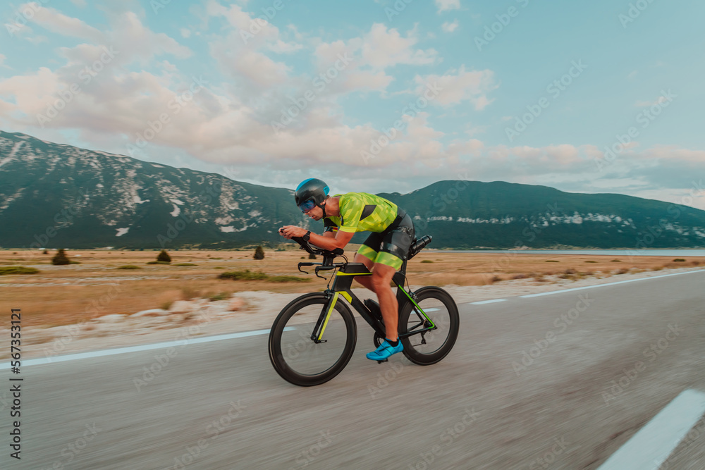 Fototapeta premium Full length portrait of an active triathlete in sportswear and with a protective helmet riding a bicycle. Selective focus 
