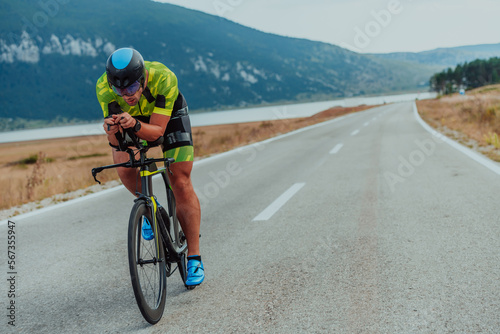 Full length portrait of an active triathlete in sportswear and with a protective helmet riding a bicycle Fototapet