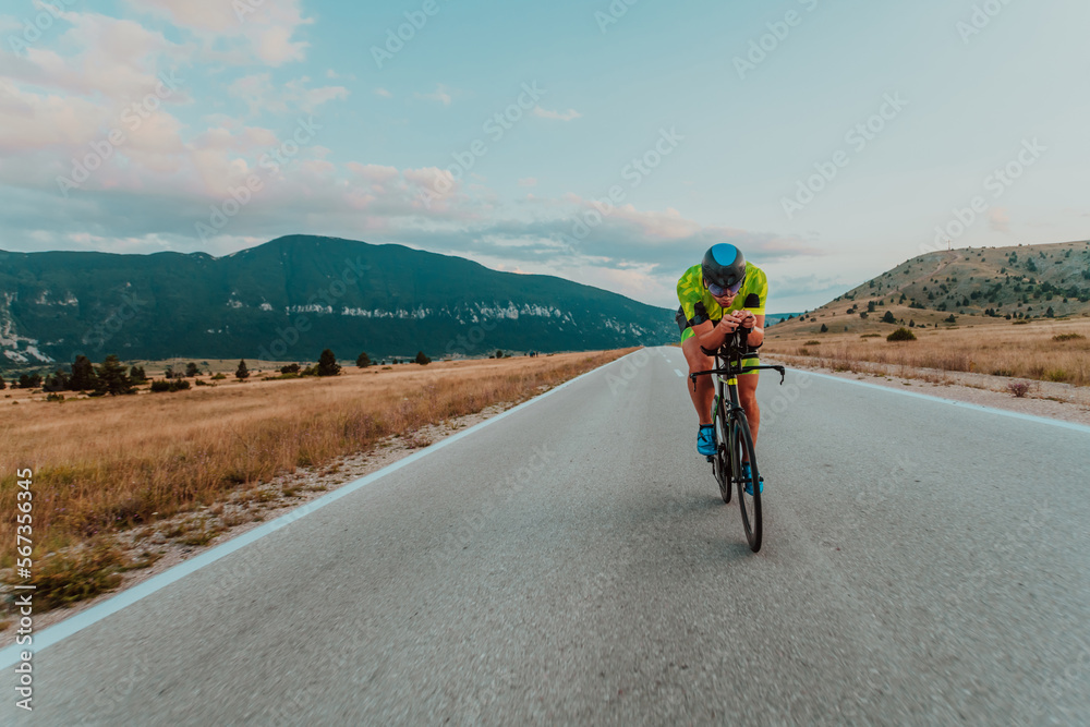 Full length portrait of an active triathlete in sportswear and with a protective helmet riding a bicycle. Selective focus Full length portrait of an active triathlete in sportswear and with a protective helmet riding a bicycle. Selective focus
