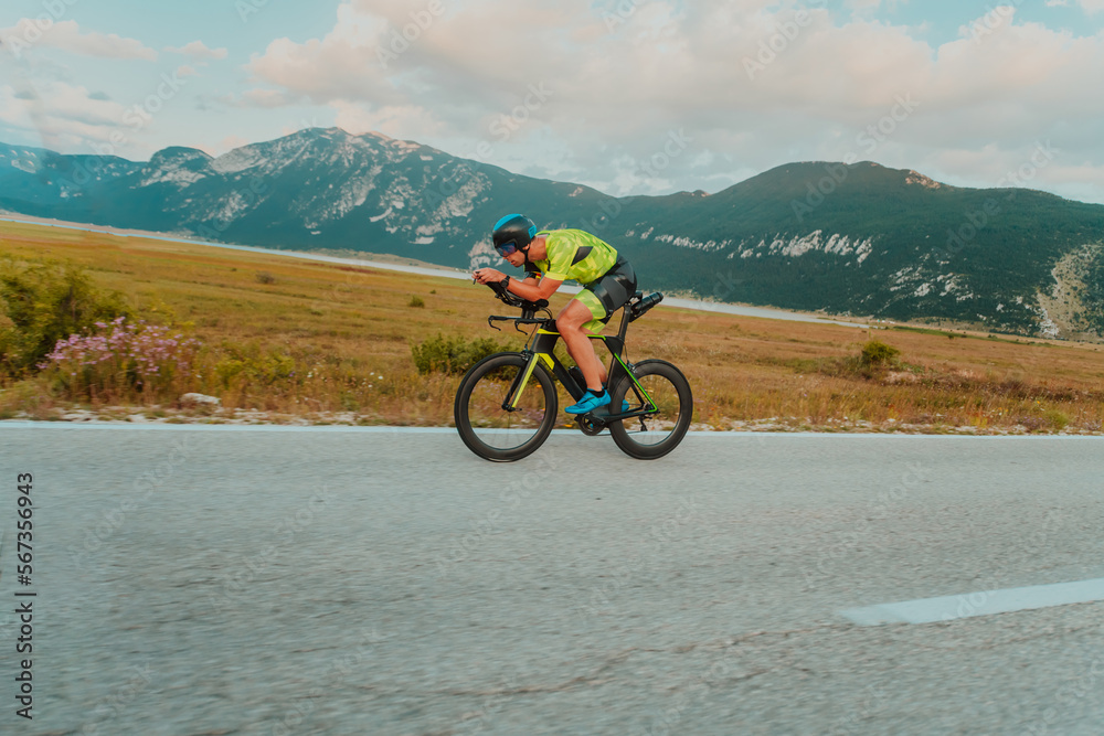 Full length portrait of an active triathlete in sportswear and with a protective helmet riding a bicycle. Selective focus Full length portrait of an active triathlete in sportswear and with a protective helmet riding a bicycle. Selective focus