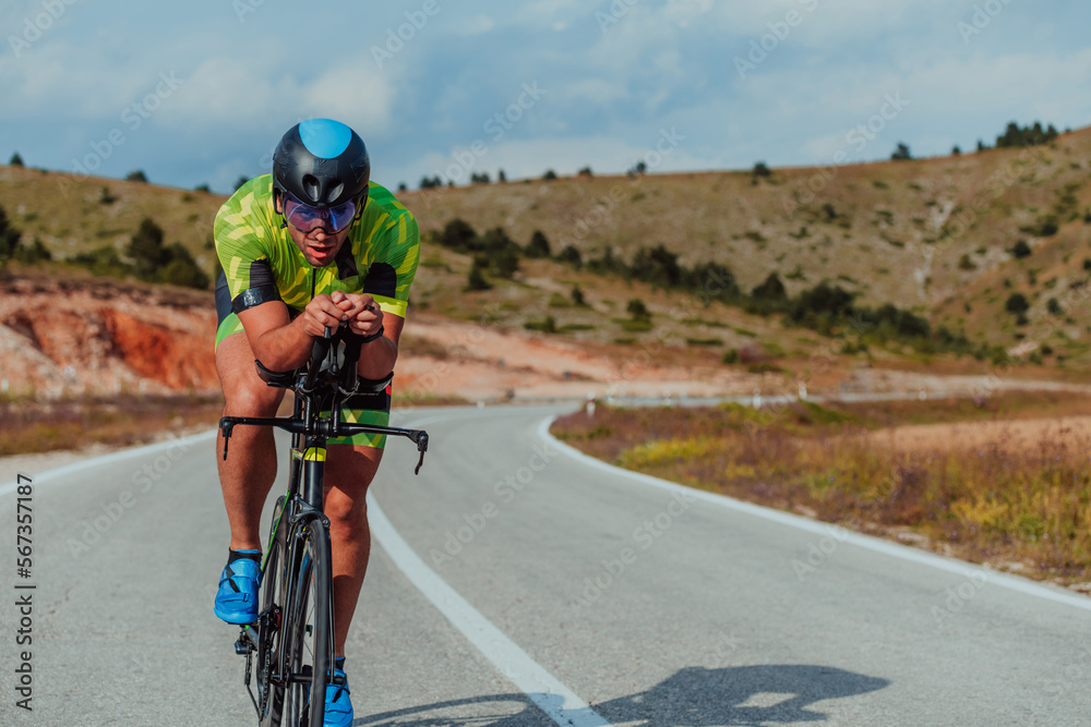 Obraz premium Full length portrait of an active triathlete in sportswear and with a protective helmet riding a bicycle. Selective focus 