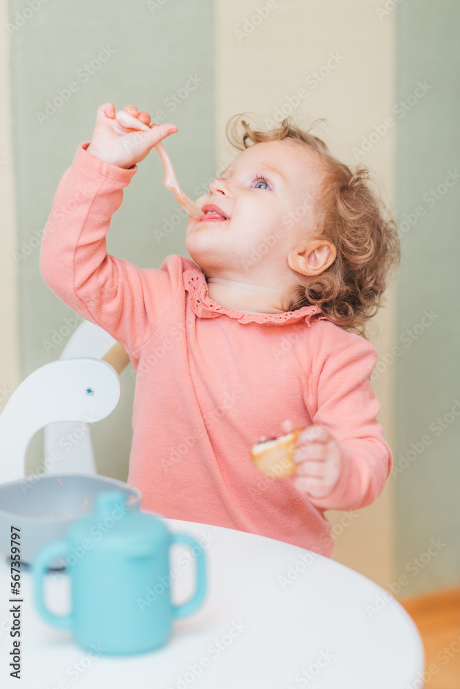 Happy little girl eating applesauce at home Happy little girl eating applesauce at home