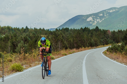 Full length portrait of an active triathlete in sportswear and with a protective helmet riding a bicycle. Selective focus  © .shock