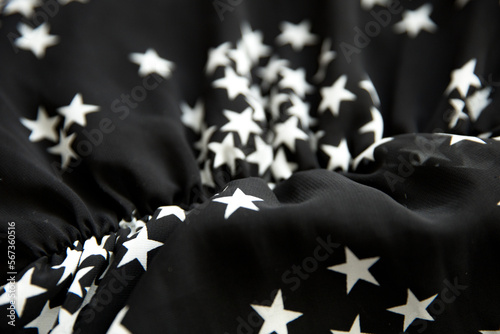 Black folded fabric with white stars pattern as texture background © kapichka