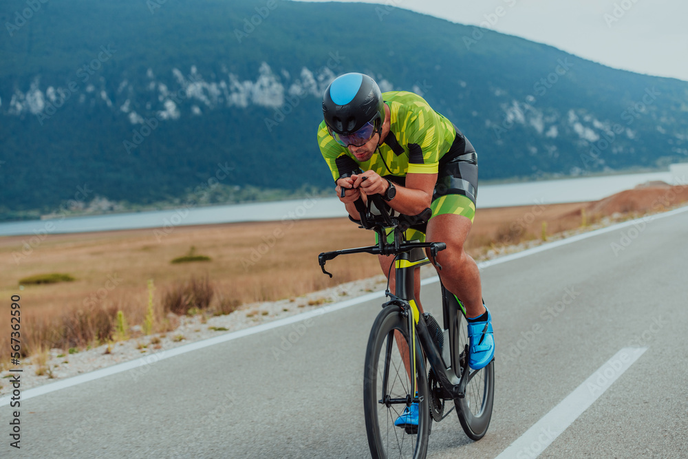 Full length portrait of an active triathlete in sportswear and with a protective helmet riding a bicycle. Selective focus 