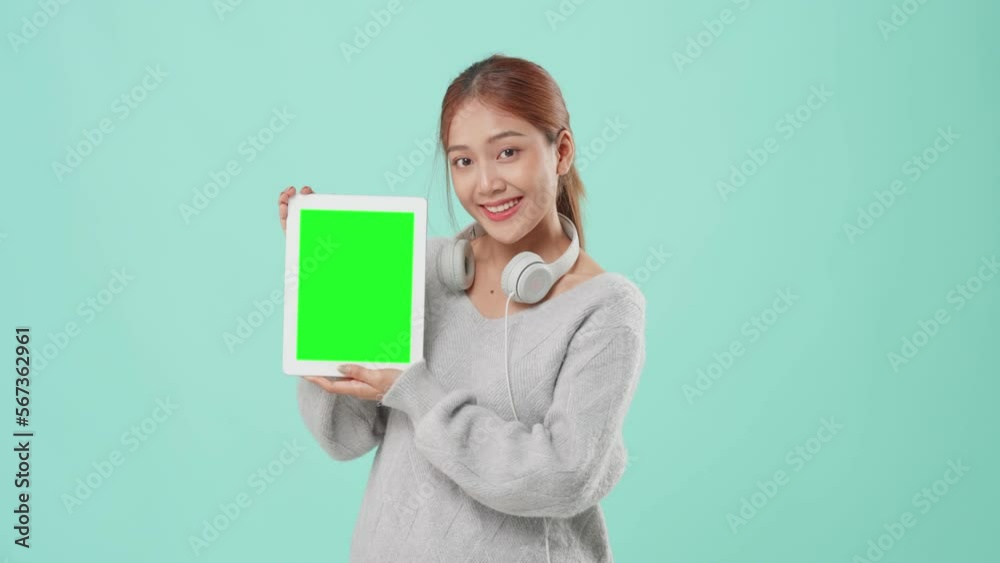 Young Asian student beautiful woman holding taplate with green screen on green background studio. Young Asian student beautiful woman holding taplate with green screen on green background studio.