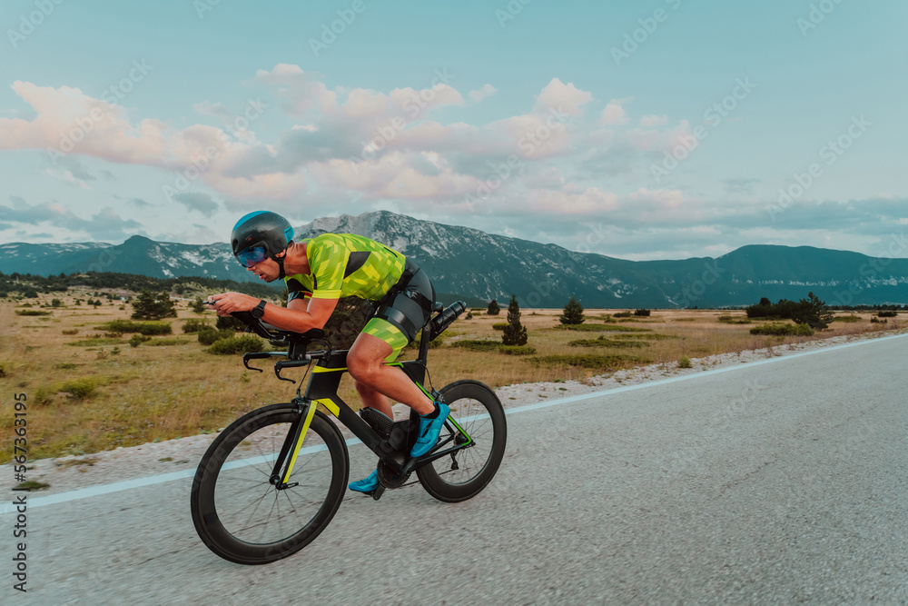 Full length portrait of an active triathlete in sportswear and with a protective helmet riding a bicycle. Selective focus Full length portrait of an active triathlete in sportswear and with a protective helmet riding a bicycle. Selective focus