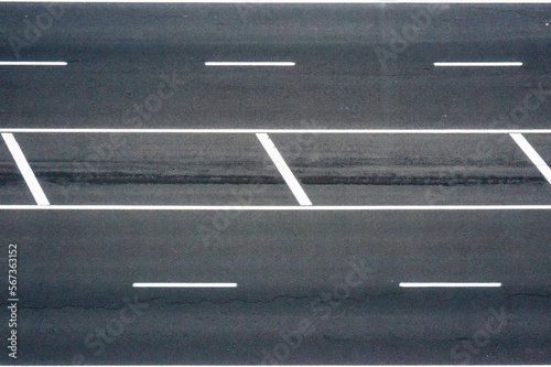 Top view of asphalt road with white strips.