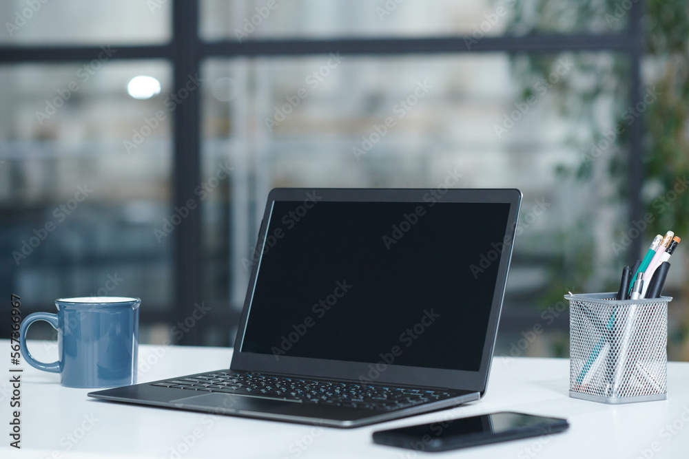 Close-u of workplace with laptop and mobile phone on table for online work at office Close-u of workplace with laptop and mobile phone on table for online work at office