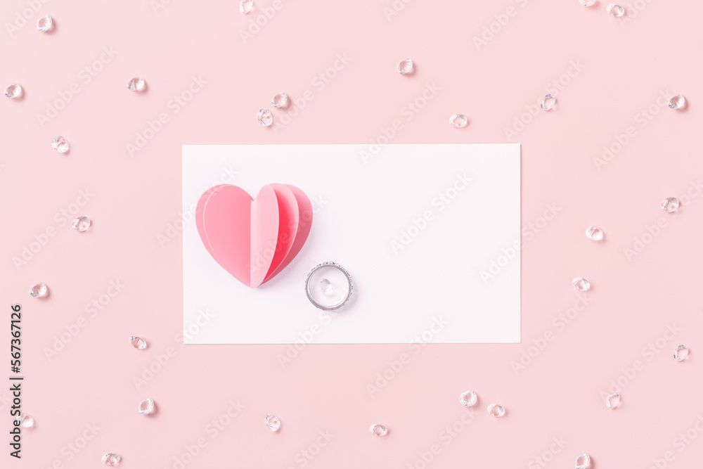 Pink heart, ring and empty white paper card for love note with sequins, rhinestones on pink background. Minimal flat lay, mock up valentine card or wedding invitation. Romantic concept