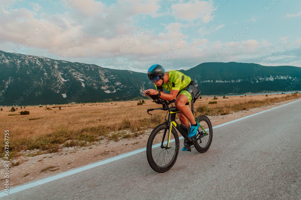 Full length portrait of an active triathlete in sportswear and with a protective helmet riding a bicycle. Selective focus Full length portrait of an active triathlete in sportswear and with a protective helmet riding a bicycle. Selective focus