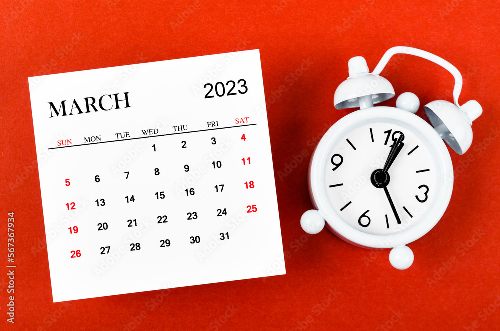 The March 2023 Monthly calendar year with alarm clock on red background. The March 2023 Monthly calendar year with alarm clock on red background.