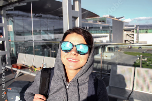 Portrait of happy smiling woman in suglasses with backpack in the airport. Travel al vactaion concept. photo