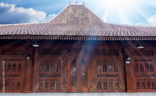 Javanese traditional house. The doors (called Gebyok), windows and walls made of carved teak wood. The tile made of clay. Sunlight with lens flare in the foreground. photo