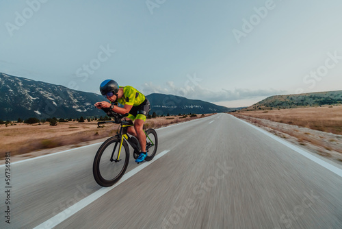 Full length portrait of an active triathlete in sportswear and with a protective helmet riding a bicycle. Selective focus 