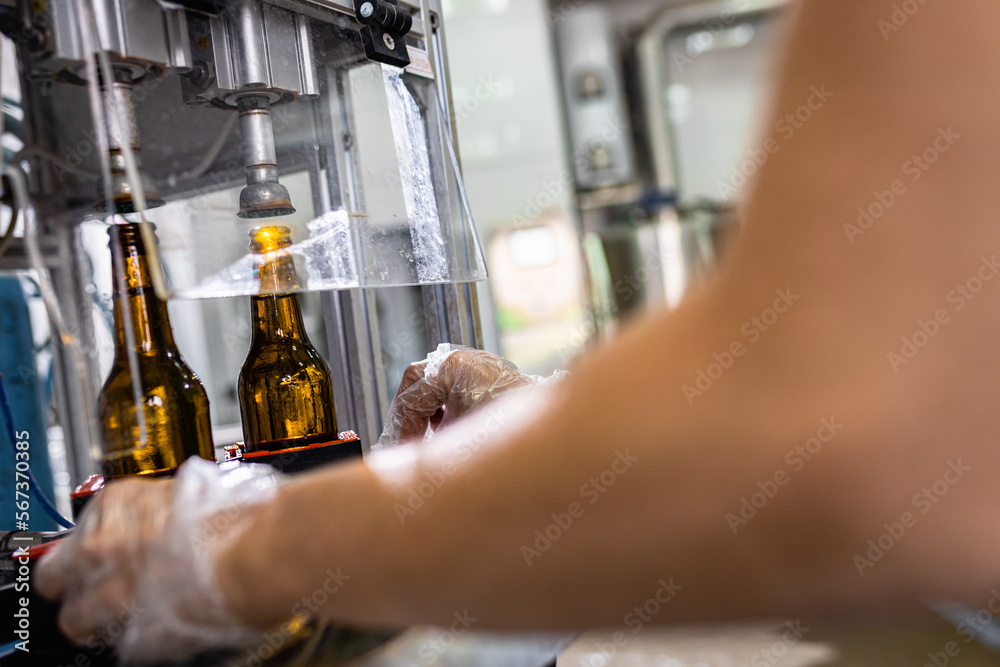 Close up of female brewer hands in a brewery filling bottles with beer.