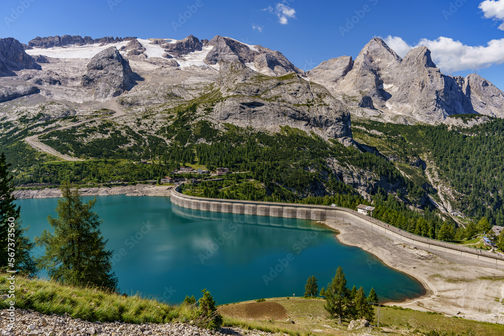 View of the mountain Marmolada covered with snow and glaciers and below the lake formed after building a dam