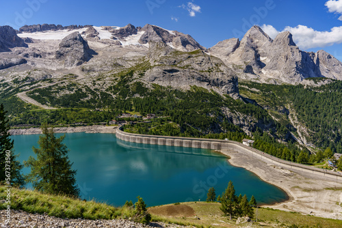 View of the mountain Marmolada covered with snow and glaciers and below the lake formed after building a dam