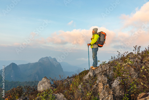Murais de parede Hiker with backpack standing on top mountain sunset background