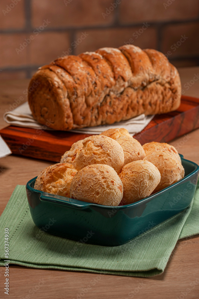Naklejka premium Cheese breads in a serving dish with wholemeal bread behinden.