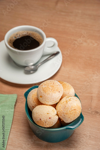 Cheese breads in a green ramekin with a cup of coffee on wooden table.