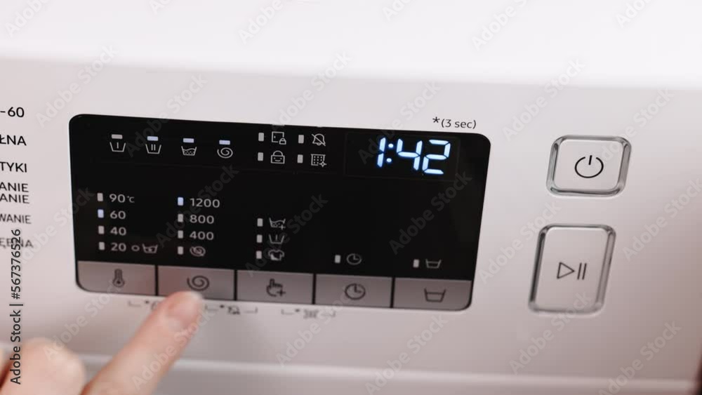 Hand turning on and off the switch of the washing machine. Person's finger turning on and off the switch of the washing machine. Domestic cleanliness and hygiene. Household chores Hand turning on and off the switch of the washing machine. Person's finger turning on and off the switch of the washing machine. Domestic cleanliness and hygiene. Household chores