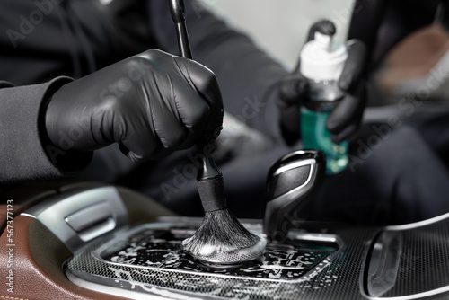Process of applying foam and detergent with a brush. A car wash service worker cleans the car inside photo
