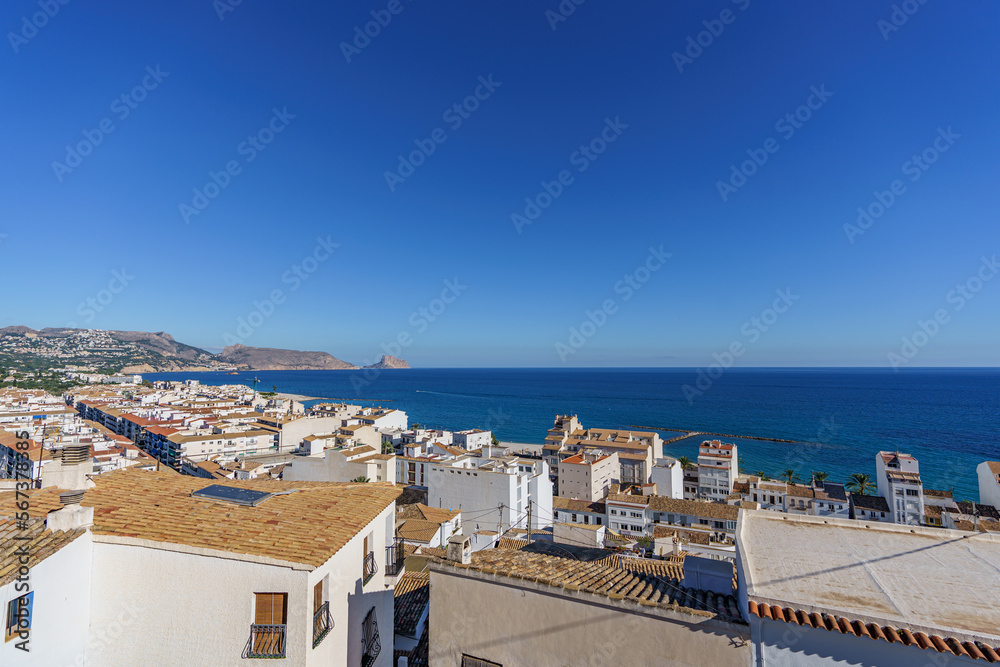 A view of the city's red tiled roofs with the sea in the background