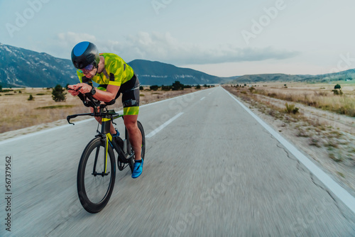 Fototapeta Naklejka Na Ścianę i Meble -  Full length portrait of an active triathlete in sportswear and with a protective helmet riding a bicycle. Selective focus 