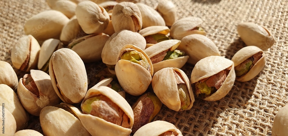 Delicious pistachios on burlap fabric. Pistachio nuts close-up. Salted pistachios. Pistachios on the table. Delicious pistachios on burlap fabric. Pistachio nuts close-up. Salted pistachios. Pistachios on the table.