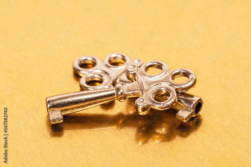Two steel keys on golden metal background Two steel keys on golden metal background