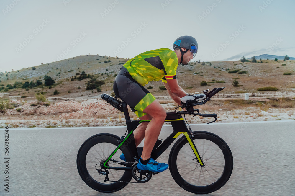 Full length portrait of an active triathlete in sportswear and with a protective helmet riding a bicycle. Selective focus Full length portrait of an active triathlete in sportswear and with a protective helmet riding a bicycle. Selective focus
