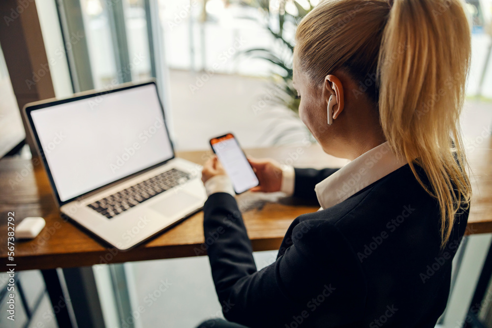 A busy woman is using technologies- phone and laptop at coffee shop and working remotely. A busy woman is using technologies- phone and laptop at coffee shop and working remotely.