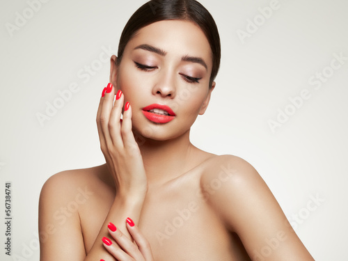 Beautiful Young Woman with clean fresh skin. Girl beauty face care. Facial treatment. Cosmetology  beauty and spa. Red nails manicure