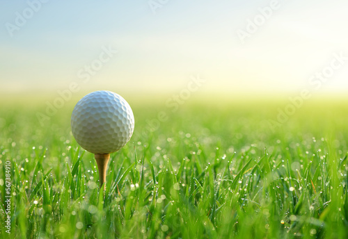 Close-up of golf ball on tee with sunrise background.