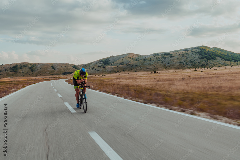 Full length portrait of an active triathlete in sportswear and with a protective helmet riding a bicycle. Selective focus Full length portrait of an active triathlete in sportswear and with a protective helmet riding a bicycle. Selective focus
