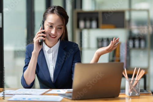 Attractive Asian businesswoman doing business related to village building project contacting using a mobile phone to chat and Negotiate management ideas in her office.