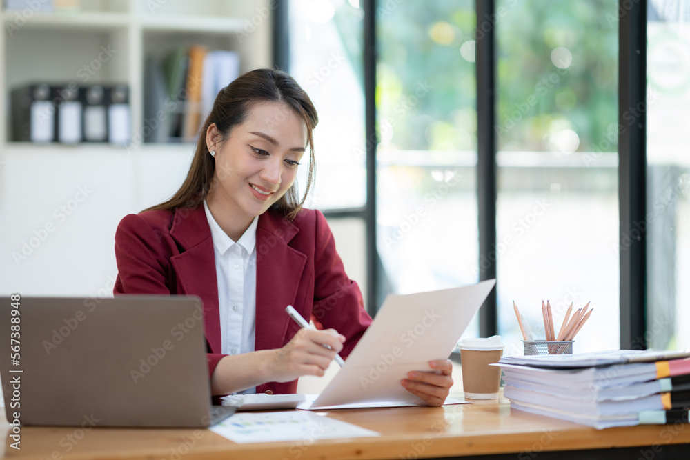 Asian businesswoman sitting happily in office holding detailed report paper analyzing data accuracy in financial matters management concept. Asian businesswoman sitting happily in office holding detailed report paper analyzing data accuracy in financial matters management concept.