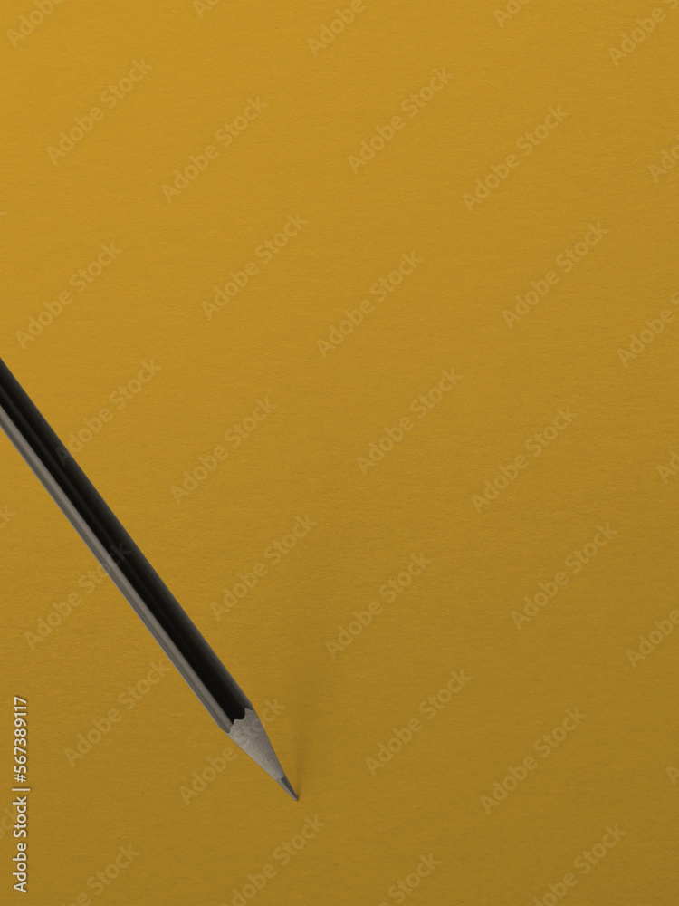 Black pencil on a background of yellow paper Black pencil on a background of yellow paper