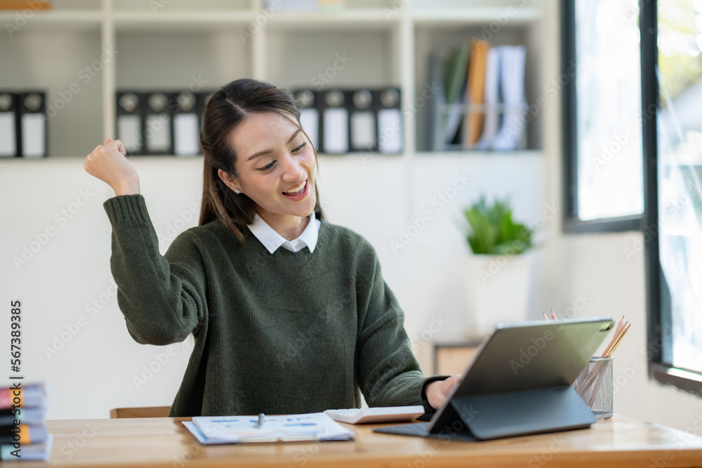 Asian businesswoman raising her hand with a happy expression to receive an email informing her about her annual bonus. concept of success. Asian businesswoman raising her hand with a happy expression to receive an email informing her about her annual bonus. concept of success.