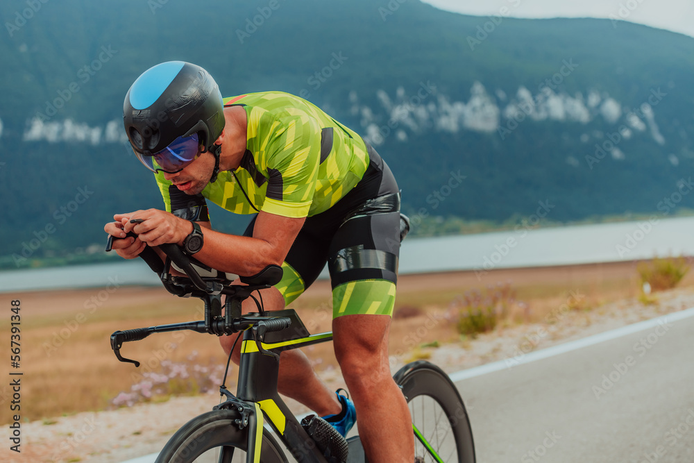 Full length portrait of an active triathlete in sportswear and with a protective helmet riding a bicycle. Selective focus 