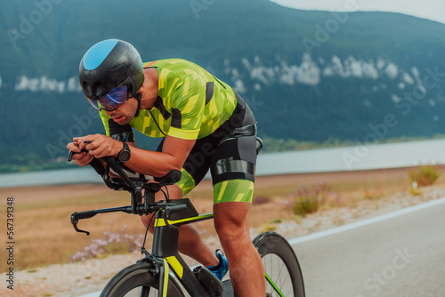 Full length portrait of an active triathlete in sportswear and with a protective helmet riding a bicycle. Selective focus 