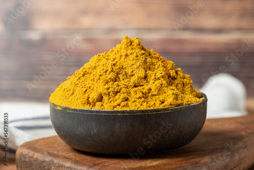 Fototapeta Naklejka Na Ścianę i Meble -  Curry Masala Powder. Turmeric powder or curry powder spice in a bowl on wooden background. İndian spices. Dry spice concept. close up