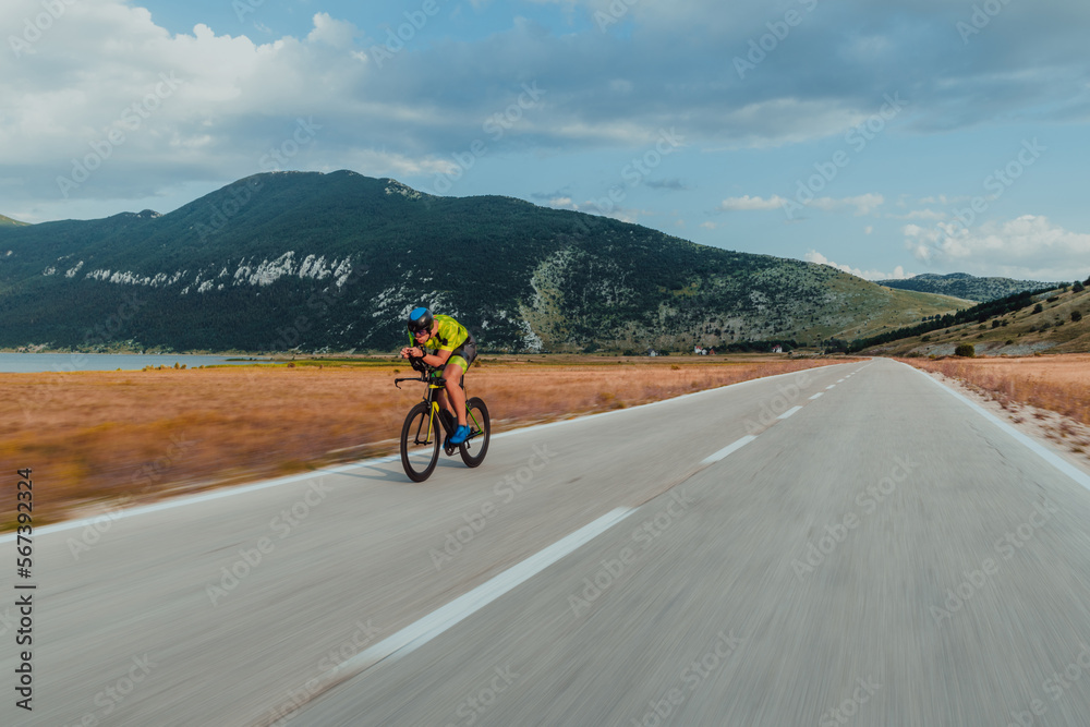 Full length portrait of an active triathlete in sportswear and with a protective helmet riding a bicycle. Selective focus Full length portrait of an active triathlete in sportswear and with a protective helmet riding a bicycle. Selective focus