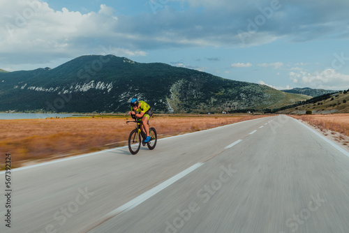 Full length portrait of an active triathlete in sportswear and with a protective helmet riding a bicycle. Selective focus 