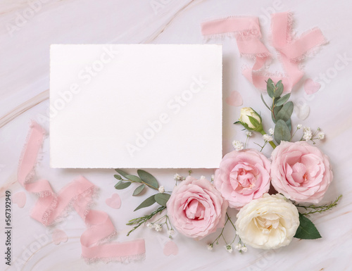 Blank paper card between pink roses and pink silk ribbons on marble top view, wedding mockup © katrinshine