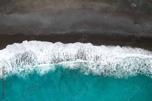 Vue aérienne d'une plage de sable noire et eau turquoise avec des vagues sur l'i Fototapet